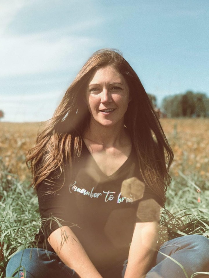 Stephanie Forgues sitting in a field on a bright sunny day.